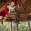 To børn sidder på en rød bjælke i børnehusets vingeslag