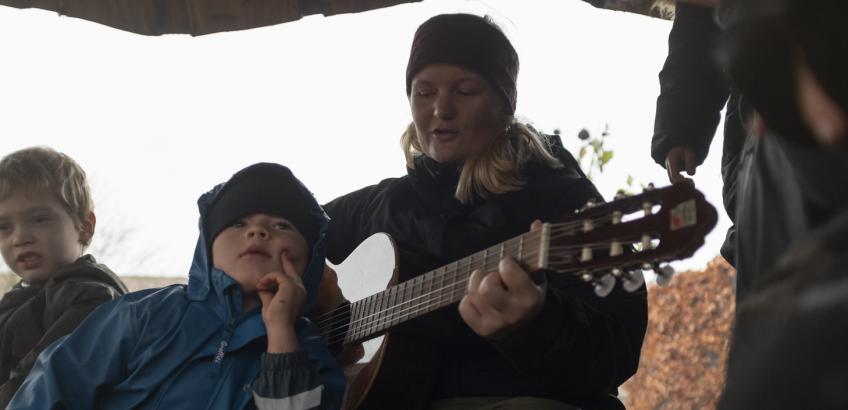 Pædagog spiller guitar for børn der lytter